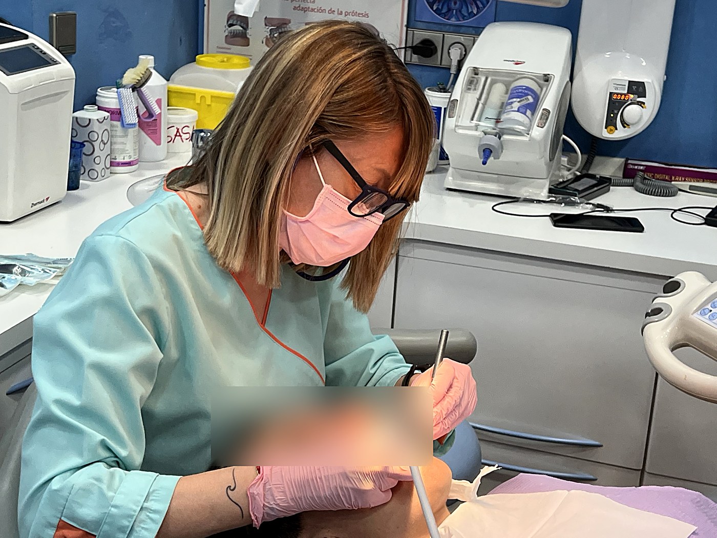 Una higienista realizando una limpieza dental a una persona en la clínica